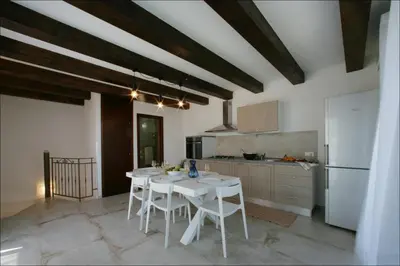 a kitchen with a white table and a white refrigerator at Villa Antonia - Vasca Idromassaggio Terrazza Vista Mare in San Vito lo Capo
