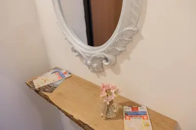 a vase of flowers on a wooden shelf with a mirror at Casa Salinas Centro Storico in Palermo