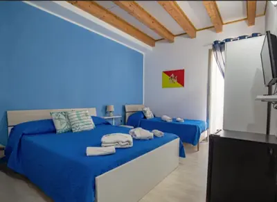 a blue bedroom with two beds and a television at GíeffeHOUSE in Terrasini