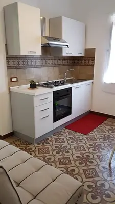 a kitchen with white cabinets and a sink and a stove at DE MEO Guest House in Castellammare del Golfo