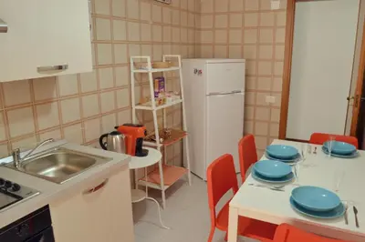 a kitchen with a white refrigerator and a table with chairs at Casa DahLia Mondello in Mondello