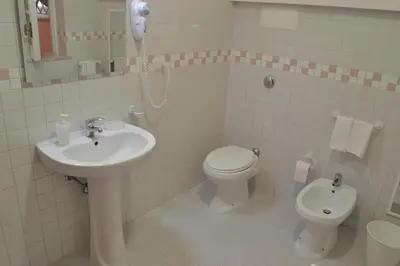 a white bathroom with a sink and a toilet at Casa DahLia Mondello in Mondello