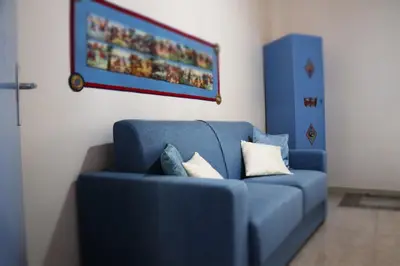 a blue couch in a room with a painting on the wall at L' Arena Suite - Sicilian style 140 mq flat with balcony and Arena seeview in Castellammare del Golfo