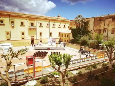 a group of people sitting in a courtyard in a building at L' Arena Suite - Sicilian style 140 mq flat with balcony and Arena seeview in Castellammare del Golfo