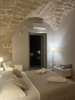 a bedroom with a large bed with a stone wall at Appartamento Valverde in Palermo