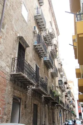 an old stone building with balconies on a street at Appartamento Valverde in Palermo