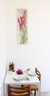 a white table with pink tulips painting on the wall at Beach House Mondello in Mondello