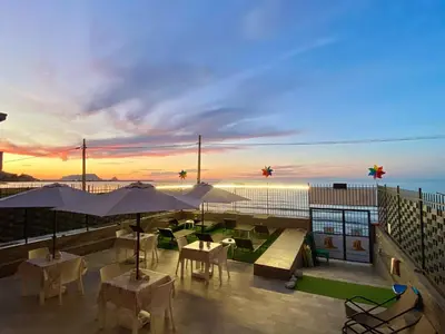 a rooftop patio with tables and umbrellas at sunset at Castello di Sabbia in Trabia