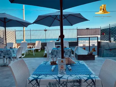 a table with chairs and an umbrella on a patio at Castello di Sabbia in Trabia