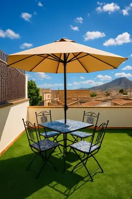 a table and chairs under an umbrella on a roof at Appartamenti Penelope in Mondello