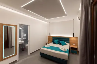 a bedroom with a bed with blue pillows and a mirror at Room & Breakfast Aloe in San Vito lo Capo