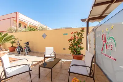a patio with chairs and plants and a wall at Room & Breakfast Aloe in San Vito lo Capo