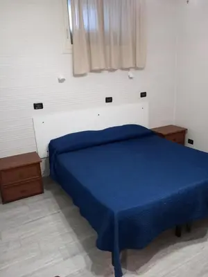 a bedroom with a blue bed and a window at Appartamenti Cavarretta Seminterrati in Mondello