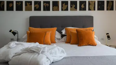 a bedroom with a bed with orange pillows at Unìco Boutique Hotel d'Arte in Mondello