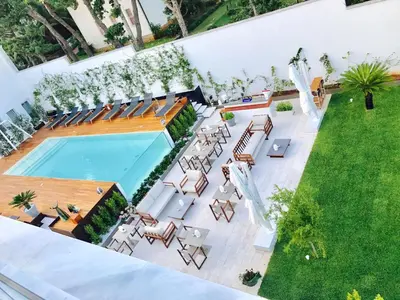 an overhead view of a swimming pool with chairs and a lawn at Unìco Boutique Hotel d'Arte in Mondello