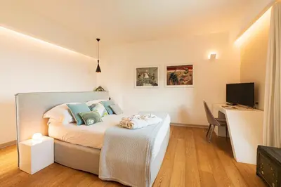 a bedroom with a bed and a desk with a television at Unìco Boutique Hotel d'Arte in Mondello