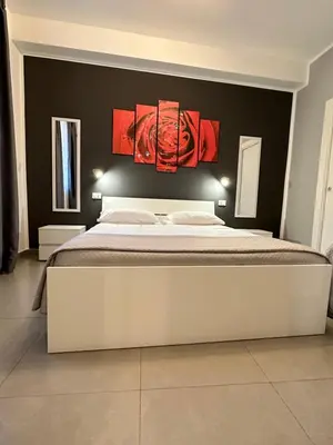 a bedroom with a large bed with red paintings on the wall at Le Tre Rose in Terrasini