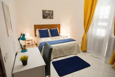 a bedroom with a bed with blue pillows and a table at Casa Benzo in Palermo