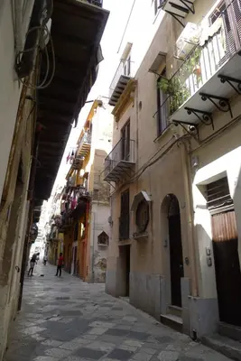 an alley with buildings and a person walking down the street at Casa Benzo in Palermo