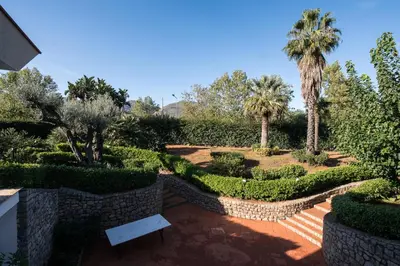 a garden with a bench and palm trees and bushes at Il Giardino di Venere in Mondello