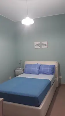 a bedroom with a bed with blue pillows at ZE-VI HOME in Santa Flavia