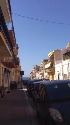 a row of cars parked on a street with buildings at Casa Escape in Terrasini
