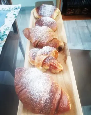 four pastries on a wooden cutting board with powdered sugar at Casa Escape in Terrasini