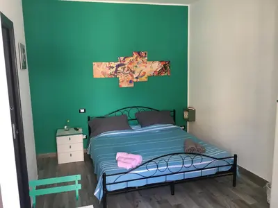 a bedroom with a bed with a green wall at Casa Escape in Terrasini
