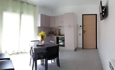 a kitchen with a table with chairs and a kitchen with white cabinets at Appartamento 