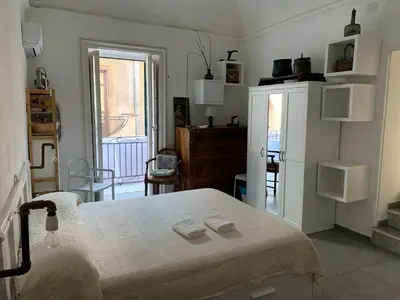 a white bedroom with a bed and a refrigerator at FraLePorte in Palermo
