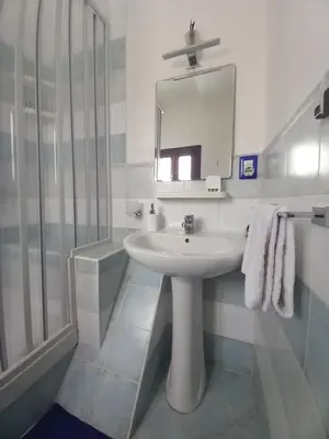 a white bathroom with a sink and a mirror at A casa SCALILLA in Palermo