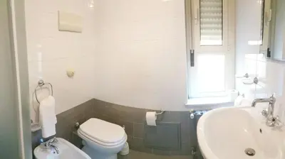 a white bathroom with a toilet and a sink at Benvenuti al Massimo in Palermo