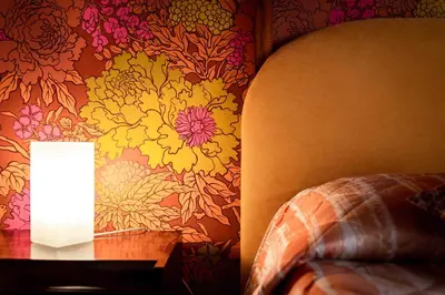 a lamp on a table next to a wall with flowers at Tetide Home in Palermo