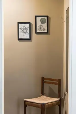 a chair and two framed pictures on a wall at Tetide Home in Palermo