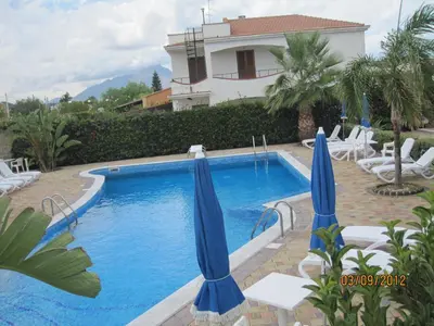 a swimming pool with two blue umbrellas and chairs at MARE AZZURRO in Campofelice di Roccella