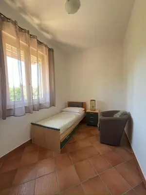 a bedroom with a bed and a chair and a window at Azienda Agrituristica Baglio Carta in Balestrate
