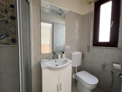 a bathroom with a sink and a toilet and a mirror at Rua House in Corleone