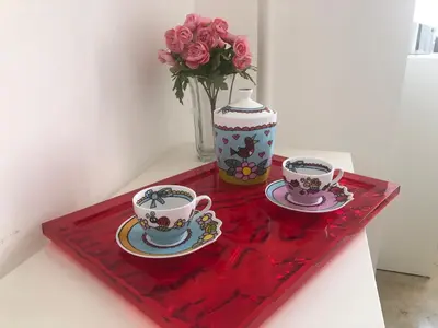 a table with two tea cups and a vase with roses at Suite Vera in Palermo