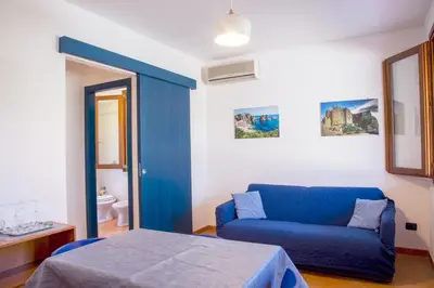 a blue couch and a bed in a room at Residence I Faraglioni in Scopello