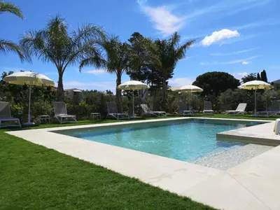 a swimming pool with chairs and umbrellas in a yard at Residence I Faraglioni in Scopello