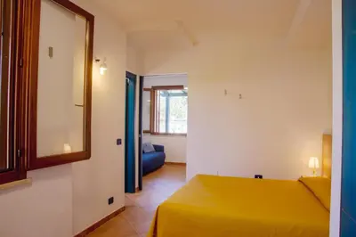 a bedroom with a yellow bed and a mirror at Residence I Faraglioni in Scopello