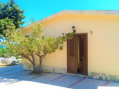 a small house with a tree in front of a door at Guidaloca Bay House con mini-piscina Scopello in Castellammare del Golfo