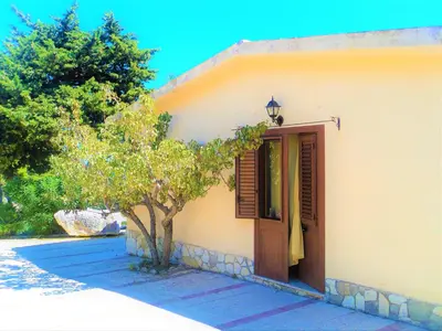 a house with a door and a tree in front of it at Guidaloca Bay House con mini-piscina Scopello in Castellammare del Golfo