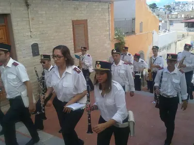 a group of men and women in uniform playing instruments at La Caletta in Santa Flavia