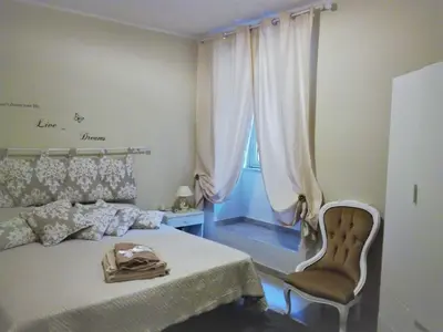 a bedroom with a bed and a chair and a window at Hello Cathedral House in Palermo