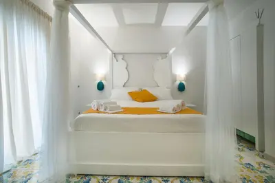 a white bedroom with a bed with white curtains at COCCIU D’AMURI in Castellammare del Golfo