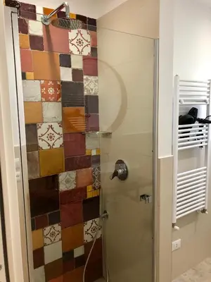 a bathroom with a shower with a colorful tile wall at COCCIU D’AMURI in Castellammare del Golfo