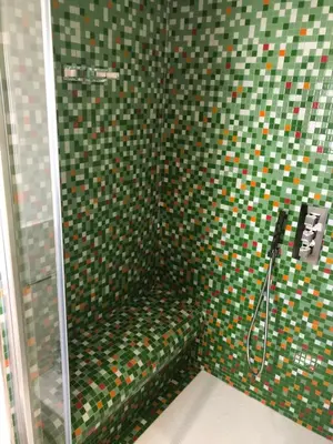 a bathroom with a shower with green and colorful tiles at COCCIU D’AMURI in Castellammare del Golfo