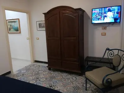 a room with a cabinet and a chair and a television at Hostel Tribunale Room Basement in Palermo