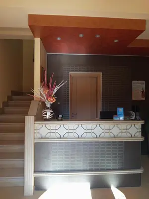 a lobby with a staircase and a vase of flowers at Amaryllis Hotel in San Vito lo Capo